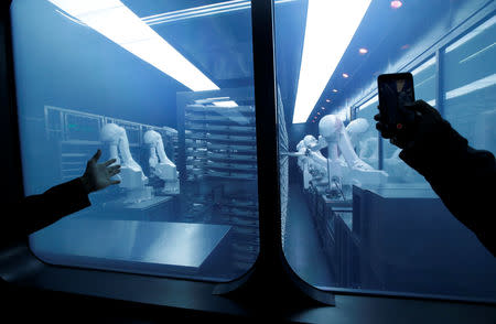 FILE PHOTO: A customer takes a picture as robotic arms collect pre-packaged dishes from a cold storage, done according to the diners' orders, at Haidilao's new artificial intelligence hotpot restaurant in Beijing, China, November 14, 2018. REUTERS/Jason Lee