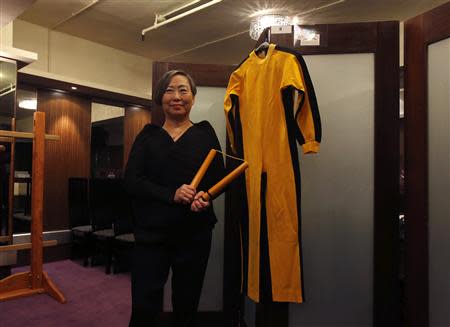 Anna Lee, vice chairman of Chinese auction house Spink, poses with nunchaku and a jumpsuit, both used by the late kungfu superstar Bruce Lee in his last movie "Game of Death", as part of the Bruce Lee 40th anniversary collection, at a news conference in Hong Kong December 2, 2013. REUTERS/Bobby Yip