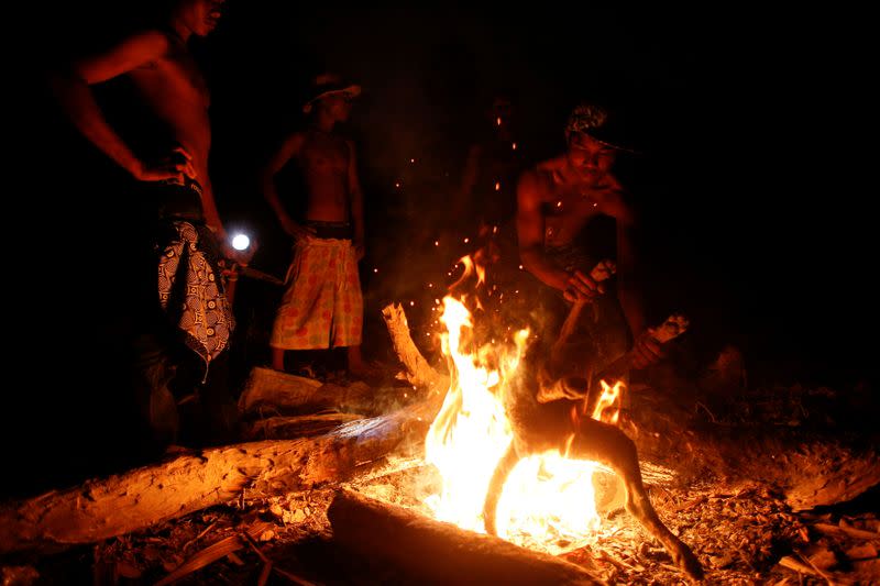 FILE PHOTO: Boys who work and live at a landfill dump site outside Siem Reap burn a dog for their dinner in Siem Reap