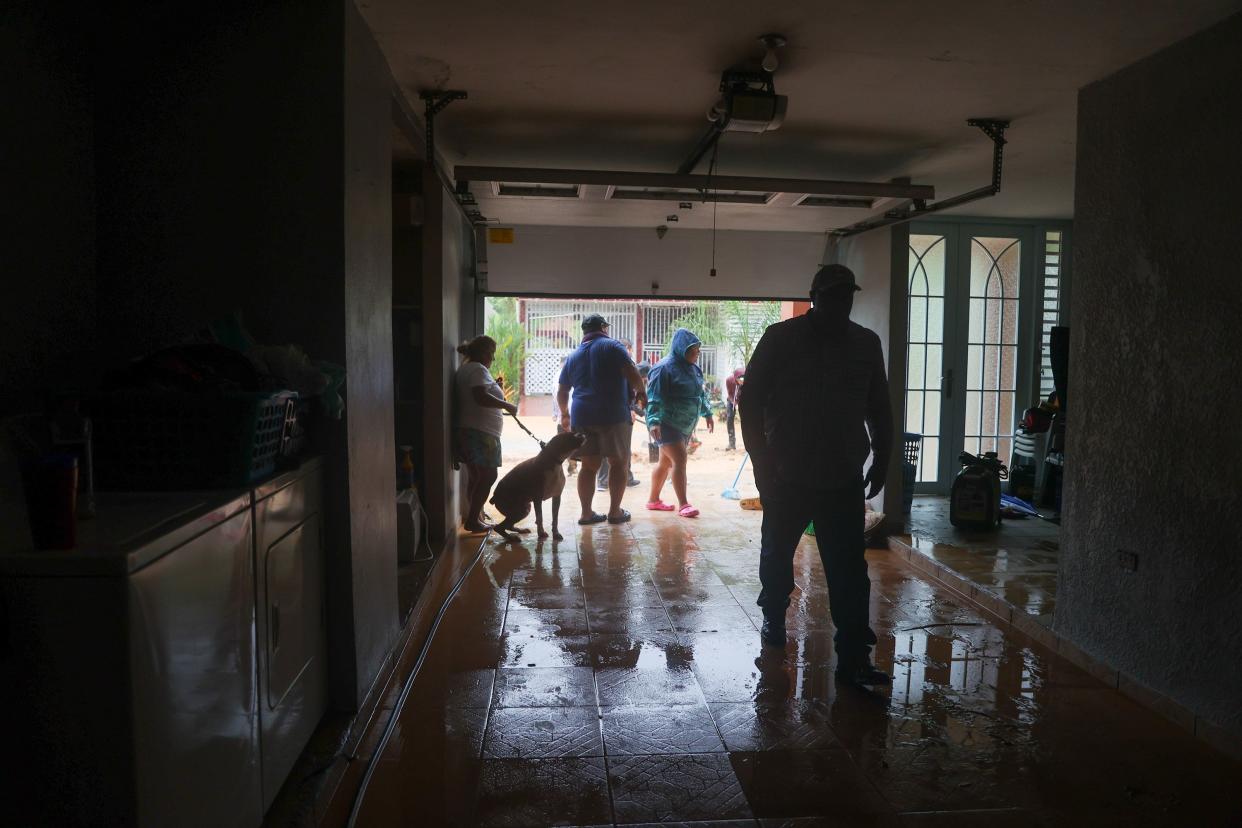 People clean a house flooded by the rains of Hurricane Fiona in Cayey, Puerto Rico, Sunday, Sept. 18, 2022.