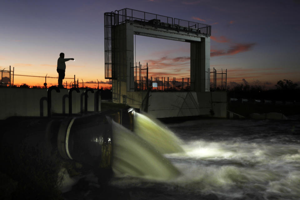 In this Monday, Oct. 28, 2019 photo, water is discharged from a flood control station along the Tamiami Trail in Miami, Fla., into a canal that drains into Everglades National Park. Heavy rains that often flood a conservation area north of the station trigger flushing of the canal, raising environmental worries about the quality of water flowing into the park. (AP Photo/Robert F. Bukaty)