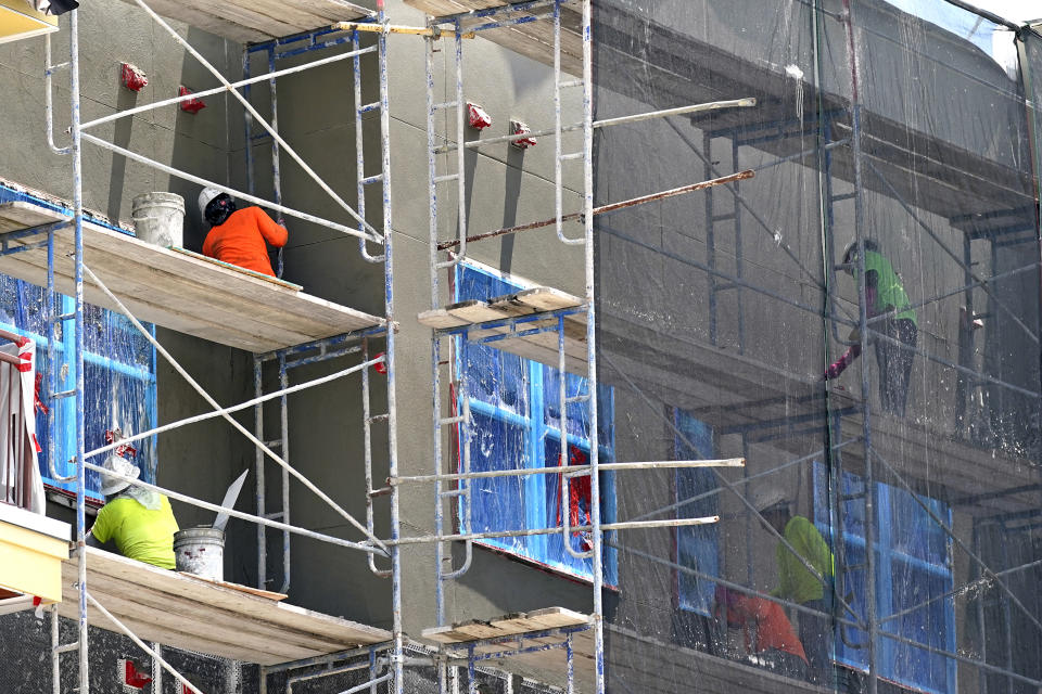 Construction workers plaster the exterior of a new apartment building, July 5, 2023, in Orlando, Fla. Undocumented workers live in fear and anxiety after a new law signed by Florida Gov. Ron DeSantis. The law targets them and employers with 25 or more employees which mandates they verify that their workers are legally allowed to work. Many workers affected are employed in the construction, agriculture and hospitality industries. (AP Photo/John Raoux)