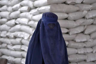 An Afghan woman waits to receive a food ration distributed by a South Korea humanitarian aid group, in Kabul, Afghanistan, Tuesday, May 10, 2022. (AP Photo/Ebrahim Noroozi)