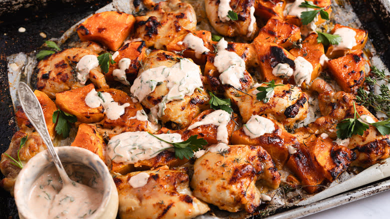 Baked chicken thighs with yogurt sauce on baking sheet