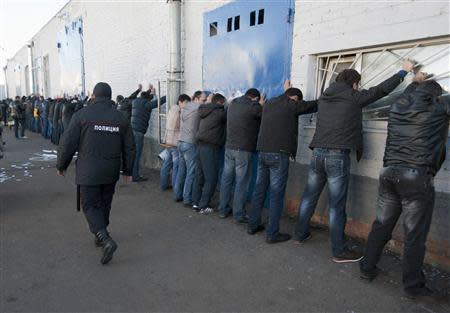 Russian police detain migrant workers during a raid at a vegetable warehouse complex in the Biryulyovo district of Moscow October 14, 2013. REUTERS/Ivan Stolpnikov