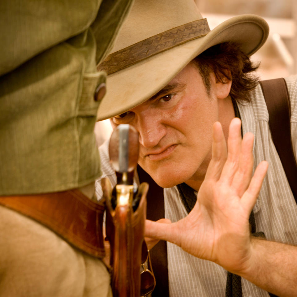 A close up of Quentin Tarantino as he leans in closely to examine a gun on someone's belt