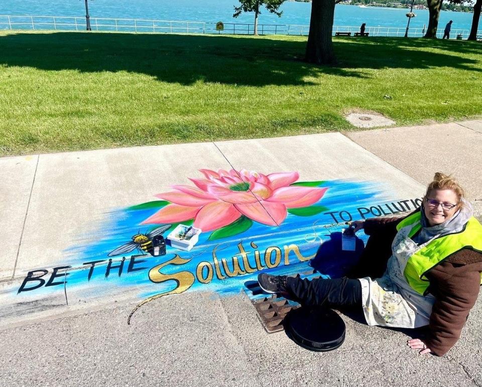 Donna Mitchell-Collins painting her mural for the Thumb Coast Storm Drain Art Project. The project aims to raise awareness to the connection between storm drains and Michigan Rivers.