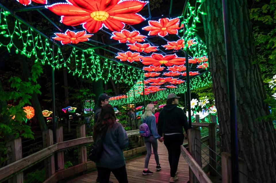 Patrons walk across an illuminated elevated footbridge during the Grand Rapids Lantern Festival at the John Ball Zoo on Wednesday, May 8, 2024.