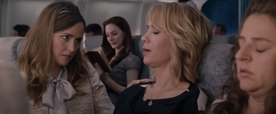 Characters from the film 'Bridesmaids' seated on a plane, creating humorous expressions