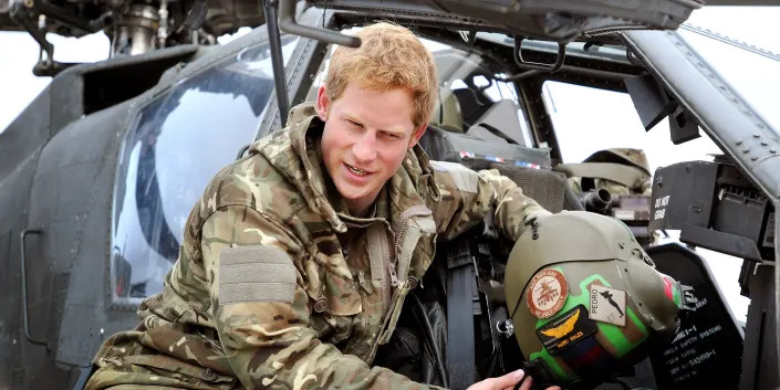 In this image released on January 21, 2013, Prince Harry, shows a television crew his flight helmet as he makes early morning checks as he sits on an Apache helicopter at the British controlled flight-line at Camp Bastion on December 12, 2012 in Afghanistan.