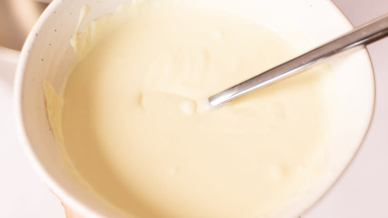 melted white chocolate in bowl with metal spoon
