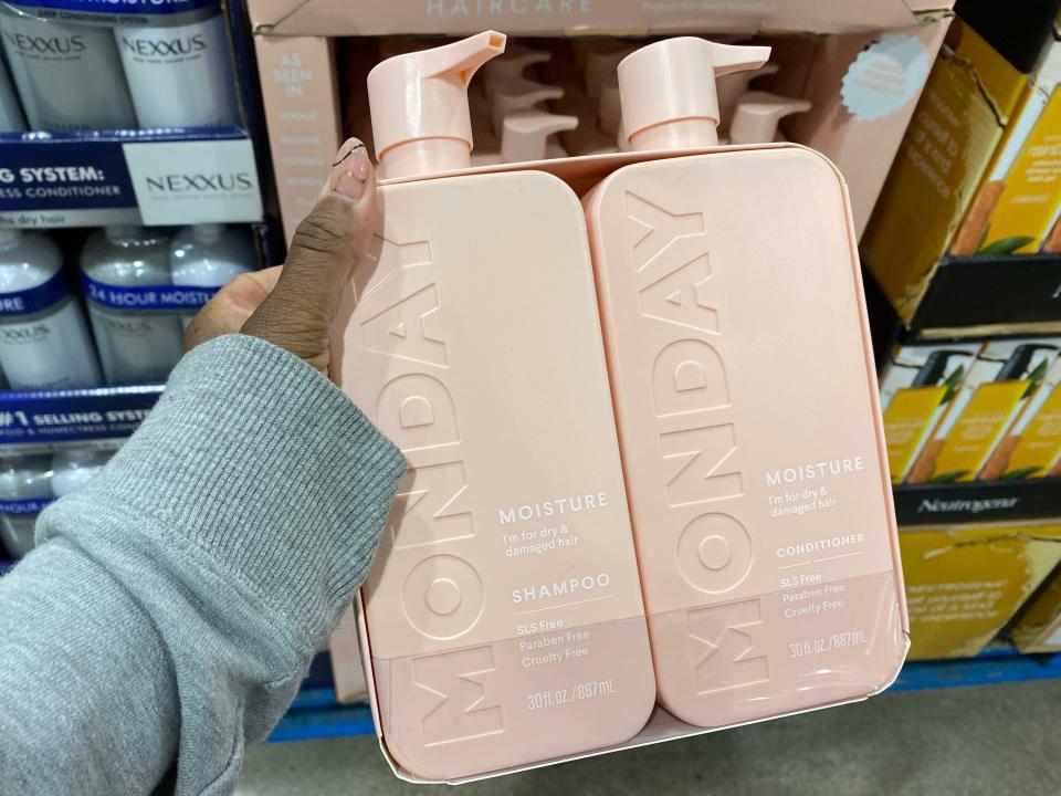 The writer holds pink pump bottles of conditioner with "Monday" written on the side