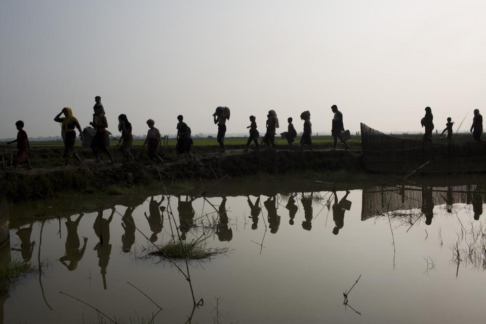 -FILE- In this Tuesday, Sept. 5, 2017, file photo members of Myanmar's Rohingya ethnic minority walk through rice fields after crossing the border into Bangladesh near Cox's Bazar's Teknaf area. Gambia has filed a case at the United Nations' highest court in The Hague, Netherlands, Monday, Nov. 11, 2019, accusing Myanmar of genocide in its campaign against the Rohingya Muslim minority. A statement released Monday by lawyers for Gambia says the case also asks the International Court of Justice to order measures "to stop Myanmar's genocidal conduct immediately." (AP Photo/Bernat Armangue, file)