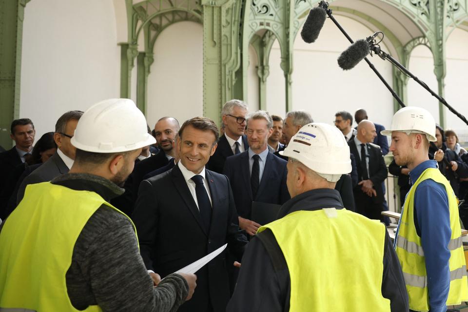 France's President Emmanuel Macron listens to workers during a visit at Le Grand Palais on Monday, 100 days ahead of the Paris 2024 Olympic Games. Le Grand Palais will host the fencing and taekwondo competition events during this summer's Olympics.