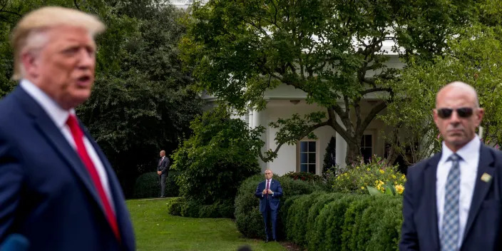 Trump stands on the left while Tony Ornato, wearing sunglasses and a suit, watches over him.