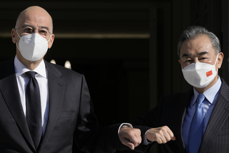 Greece's Foreign Minister Nikos Dendias, left, welcomes his Chinese counterpart Wang Yi prior to their meeting, in Athens, on Wednesday, Oct. 27, 2021. (AP Photo/Petros Giannakouris)