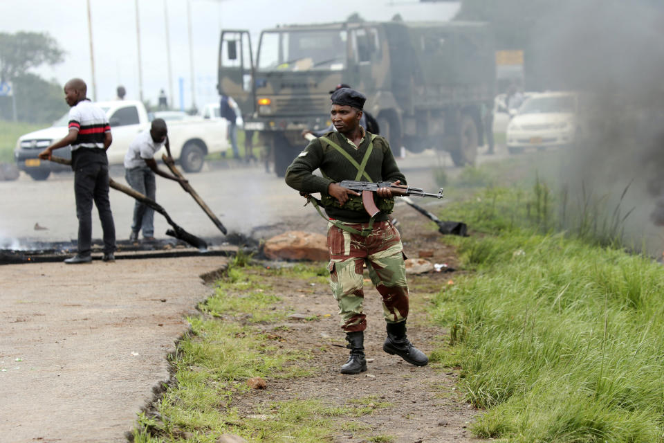 A soldier patrols as a barricade is removed during a demonstration over the hike in fuel prices in Harare, Zimbabwe, Tuesday, Jan. 15, 2019. A Zimbabwean military helicopter on Tuesday fired tear gas at demonstrators blocking a road and burning tires in the capital on a second day of deadly protests after the government more than doubled the price of fuel in the economically shattered country. (AP Photo/Tsvangirayi Mukwazhi)