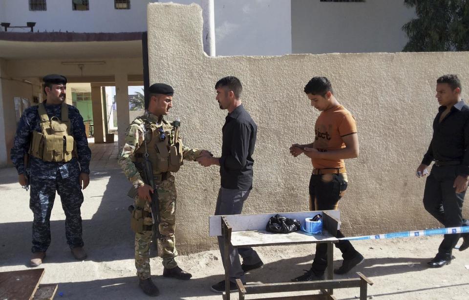 Security forces search people outside a polling station in Habaniyah town, near Fallujah Iraq, Wednesday, April 30, 2014. Local police reported several mortar attacks in Amiriyat al-Fallujah and Habaniyah town near Fallujah, near some voting centers that led to the injury of two persons. Iraq is holding its third parliamentary elections since the U.S.-led invasion that toppled dictator Saddam Hussein. More than 22 million voters are eligible to cast their ballots to choose 328 lawmakers out of more than 9,000 candidates. (AP Photo)