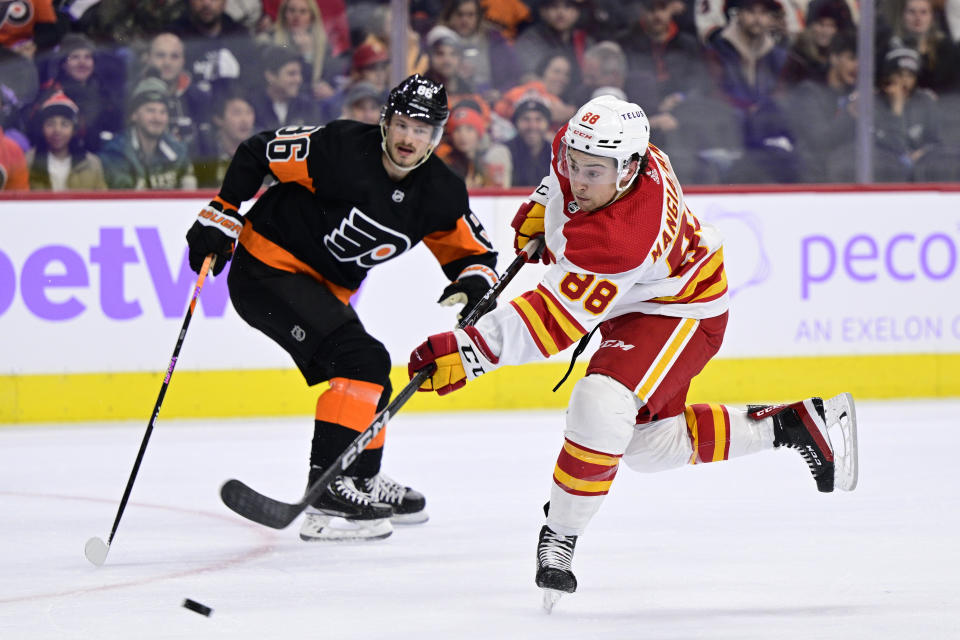 Calgary Flames' Andrew Mangiapane, right, takes a shot past the defense of Philadelphia Flyers' Joel Farabee during the first period of an NHL hockey game, Monday, Nov. 21, 2022, in Philadelphia. (AP Photo/Derik Hamilton)