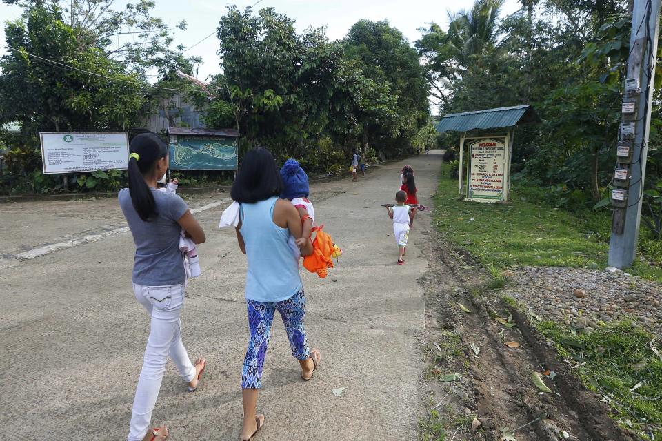 In this Jan. 27, 2019, photo, residents walk to attend a Sunday Mass at the chapel built by American priest Father Pius Hendricks in the village of Talustusan on Biliran Island in the central Philippines. In addition to the construction of the chapel, Hendricks pressed officials to pave the village road. (AP Photo/Bullit Marquez)