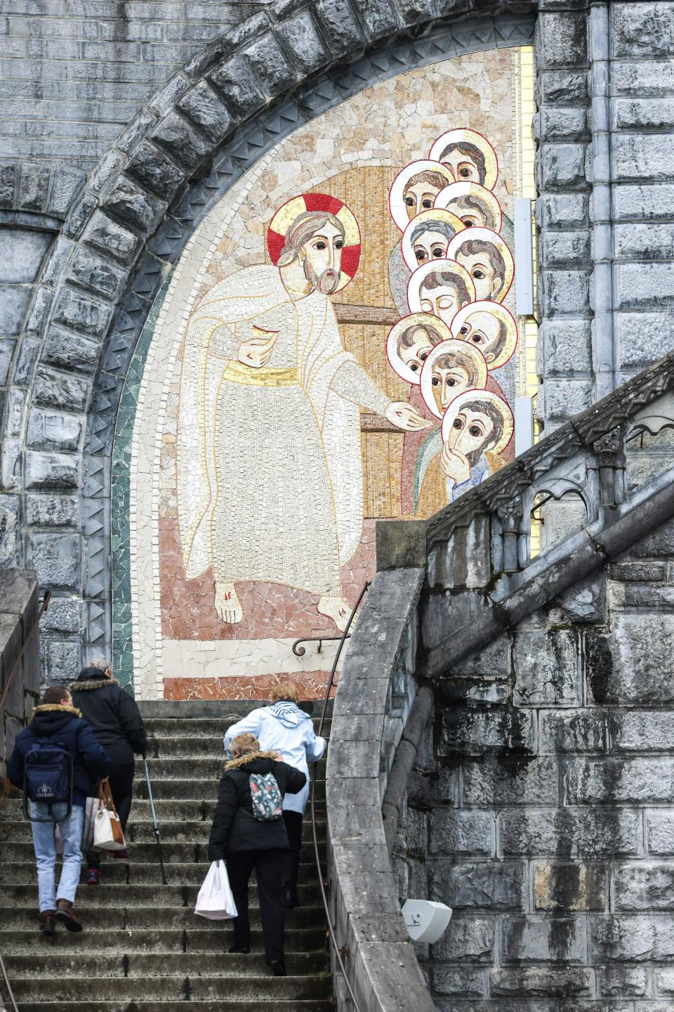 Pedestrians walk past gigantic mosaics in March 2023 displayed on the Notre-Dame-du-Rosaire Basilica in the Sanctuary of Lourdes in southwestern France.