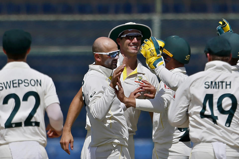 Australia's Nathan Lyon, center, celebrates with teammates after taking the wicket of Pakistan Imam-ul-Haq during the third day of the second test match between Pakistan and Australia at the National Stadium in Karachi, Pakistan, Monday, March 14, 2022. (AP Photo/Anjum Naveed)