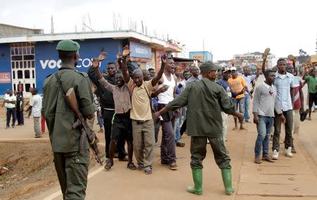 Congolese soldiers stand guard as civilians chant slogans during a protest against the government's failure to stop the killings and inter-ethnic tensions in the town of Butembo, North Kivu province in the Democratic Republic of Congo, August 24, 2016. REUTERS/Kenny Katombe