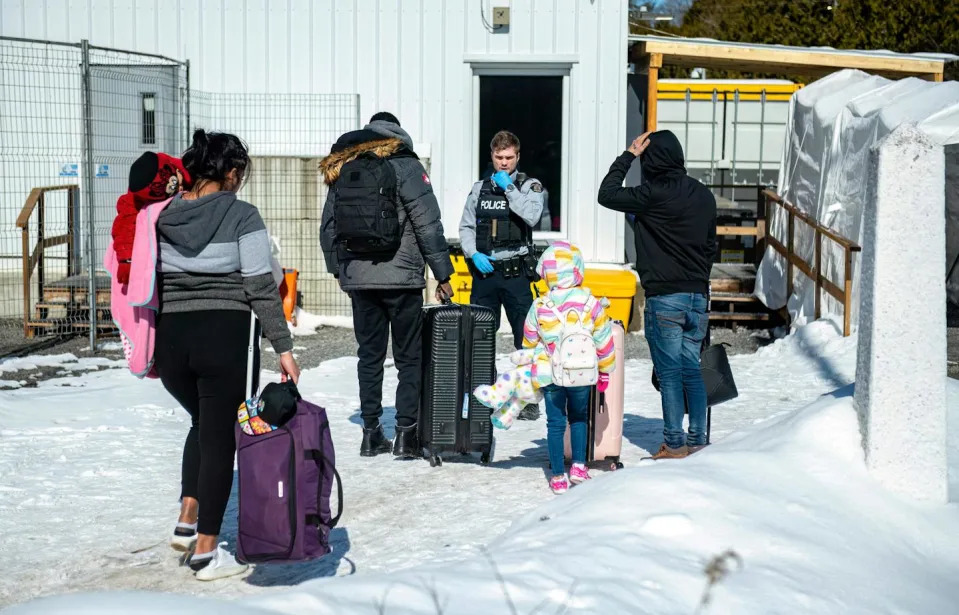 A Canadian officer speaks to migrants as they arrive in Quebec in March 2023. <a href=