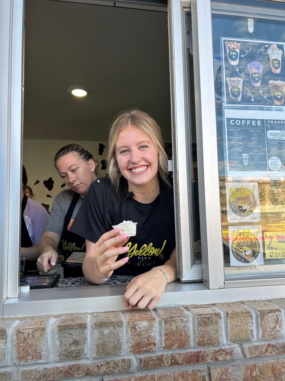 Cambree Thompson at Yellow City Grind, hands off a Pup Cup, whipped cream in a cup, to a grateful canine.