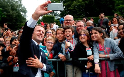 French President Emmanuel Macron (C) takes a 'selfie' with members of the crowd at the Mont Valérien national memorial in Suresnes near Paris - Credit: CHARLES PLATIAU/AFP