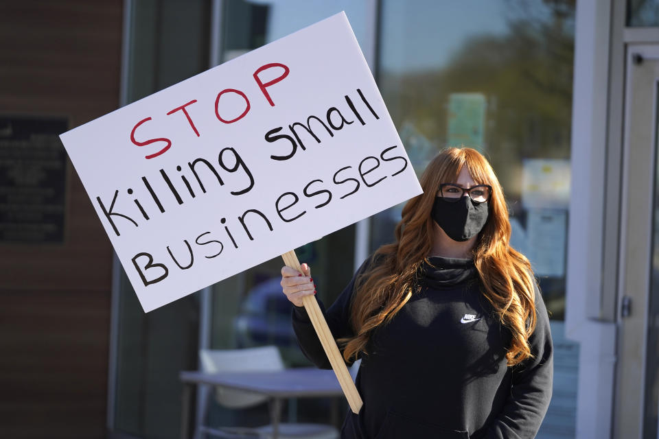 Lisa Kreyer holds up a sign during a protest by hair salon owners and workers against the latest lockdown orders outside the offices of Marin County Health Officer Dr. Matt Willis Thursday, Dec. 10, 2020, in San Rafael, Calif. California health officials are urging the state's residents to stay home as much as possible due to a coronavirus surge taxing the state's hospitals. But the most recent stay-at-home order allows some businesses to remain open, frustrating shuttered business owners who say officials keep sending mixed messages. (AP Photo/Eric Risberg)