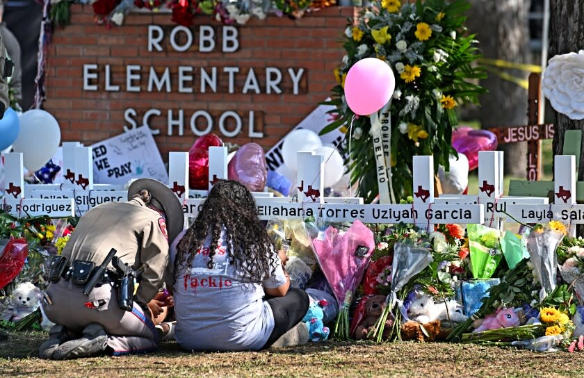 Uvalde, Texas May 26, 2022- A police officer comforts family members at a memorial outside Rob Elementary School in Uvalde, Texas. Nineteen students and two teachers died when a gunman opened fire in a classroom Tuesday. (Wally Skalij/Los Angeles Times)