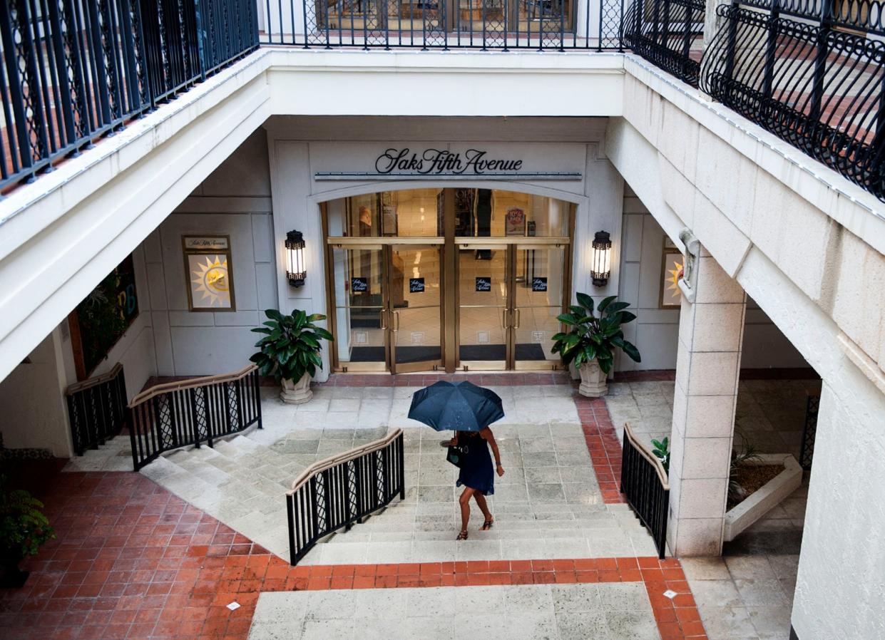 A pedestrian uses an umbrella during a June 2021 storm at The Esplanade on Worth Avenue. The town's merchants are expecting a robust retail season this fall and winter.