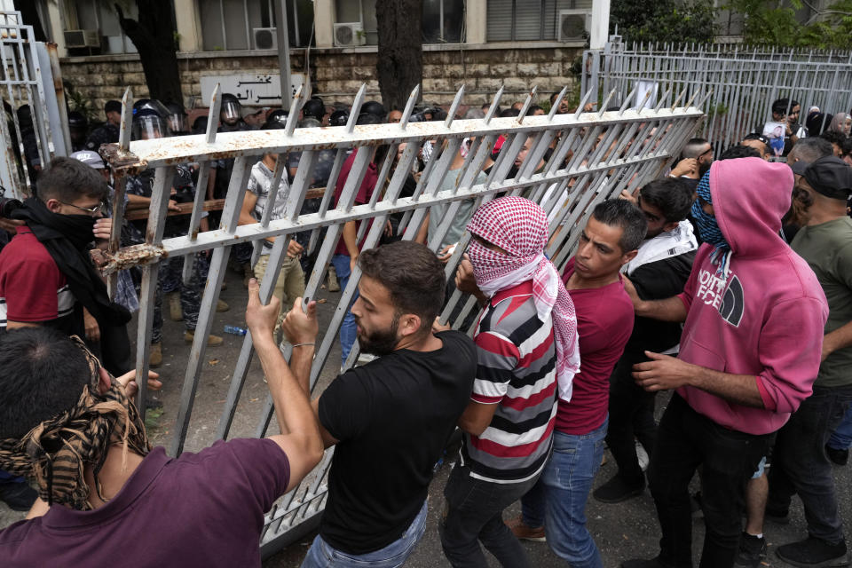 Protesters try to remove a gate to the Justice Palace during a demonstration demanding the release of two people arrested last week during a bank robbery, in Beirut, Lebanon, Monday, Sept. 19, 2022. Anger with local lenders who have been imposing informal capital controls including limits on ATM withdrawals for nearly three years increased in recent weeks, with some depositors storming bank branches and taking their trapped savings by force. (AP Photo/Bilal Hussein)