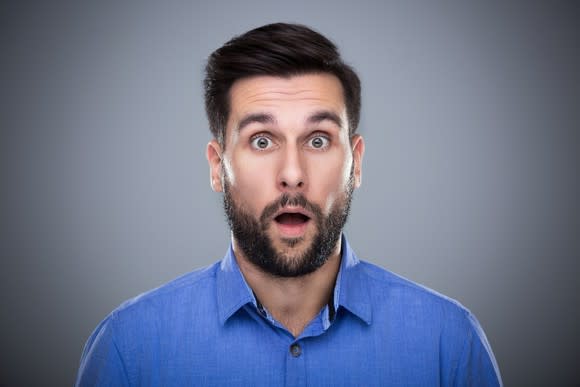 A man with a beard looks into the camera with a surprised open-mouth expression.