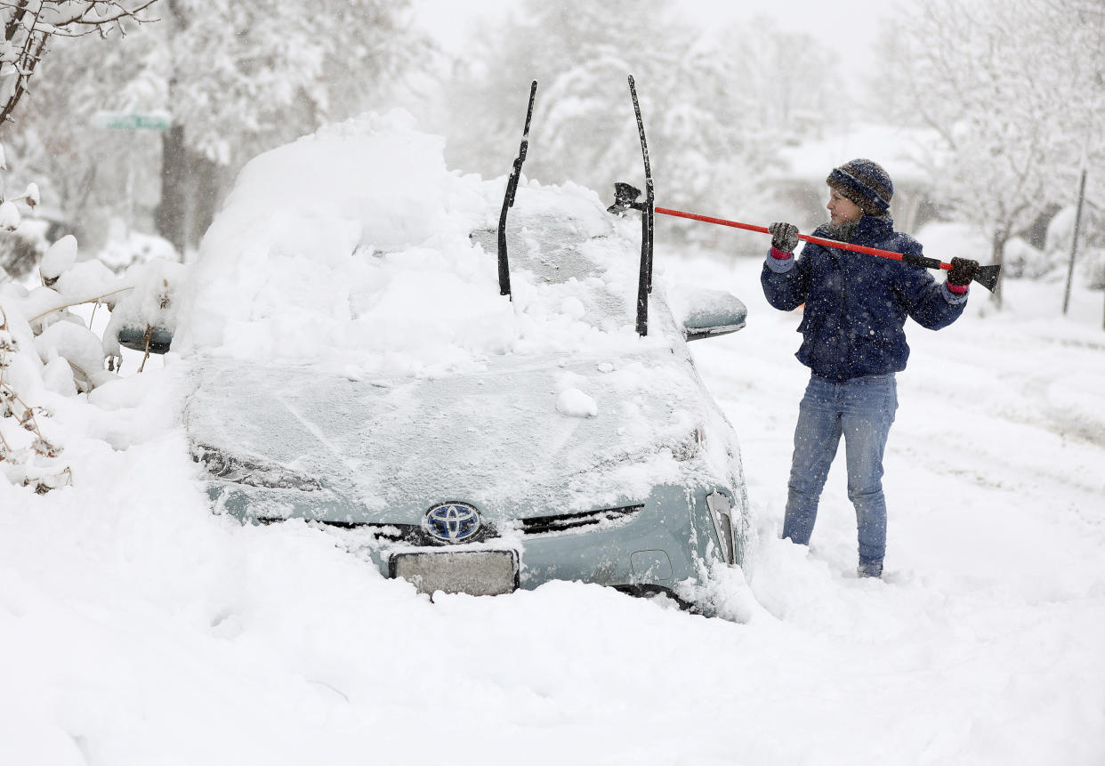 Cathy Morgan-Mace cleans snow and ice off her family's car during a snowstorm in Salt Lake City, Utah, on Wednesday, Feb. 22, 2023. (Kristin Murphy/The Deseret News via AP)