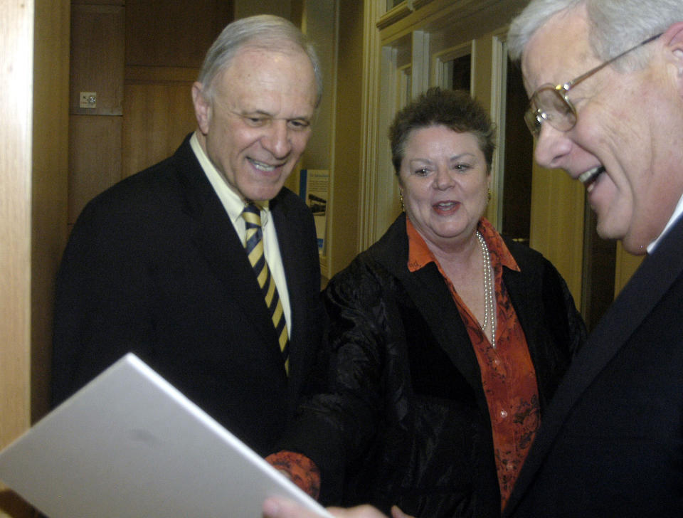 FILE - David Pryor, left, a former senator, governor and founding dean of the University of Arkansas' Clinton School of Public Service; his wife Barbara, center; and Alan Sugg, president of the University of Arkansas System, look at an old photo of Pryor during a celebration for his last day as dean of the school, Feb. 15, 2006, in Little Rock, Ark. Former Arkansas governor and U.S. Sen. David Pryor, a Democrat who was one of the state’s most beloved political figures and remained active in public service in the state long after he left office, has died. He was 89. (AP Photo/Mike Wintroath, File)