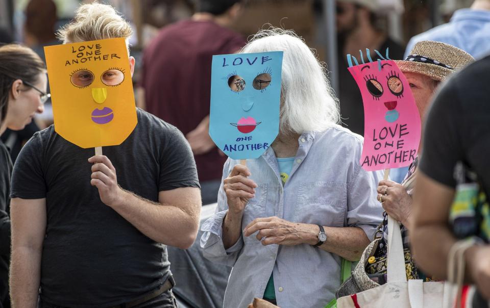 Demonstrators stand in front of the Schooner Creek Farm booth in August 2019 at the Bloomington Community Farmers’ Market. Authorities determined the masks constituted a sign and were asked to not display them. The demonstrators stopped with no incident.