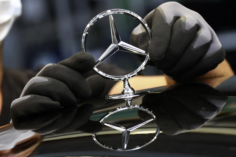 FILE - In this Thursday, April 30, 2020 file photo, an employee attaches a Mercedes emblem as he works on a Mercedes-Benz S-class car at the Mercedes plant in Sindelfingen, Germany. Daimler, maker of Mercedes-Benz vehicles, is reporting third-quarter earnings on Friday Oct. 22, 2020. (AP Photo/Matthias Schrader, file)