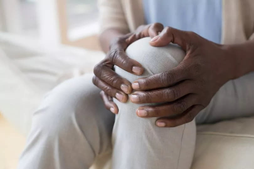 Mature woman holding sore knee.