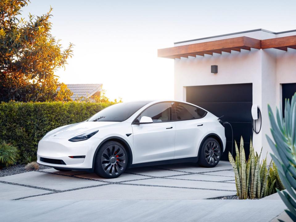 The Tesla Model Y electric SUV charging at a home.