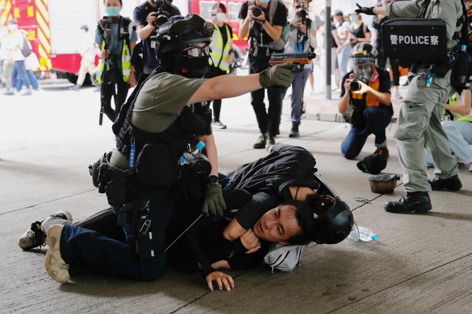 A police officer raises his pepper spray handgun as he detains a man during a march against the national security law at the anniversary of Hong Kong's handover to China from Britain in Hong Kong: REUTERS