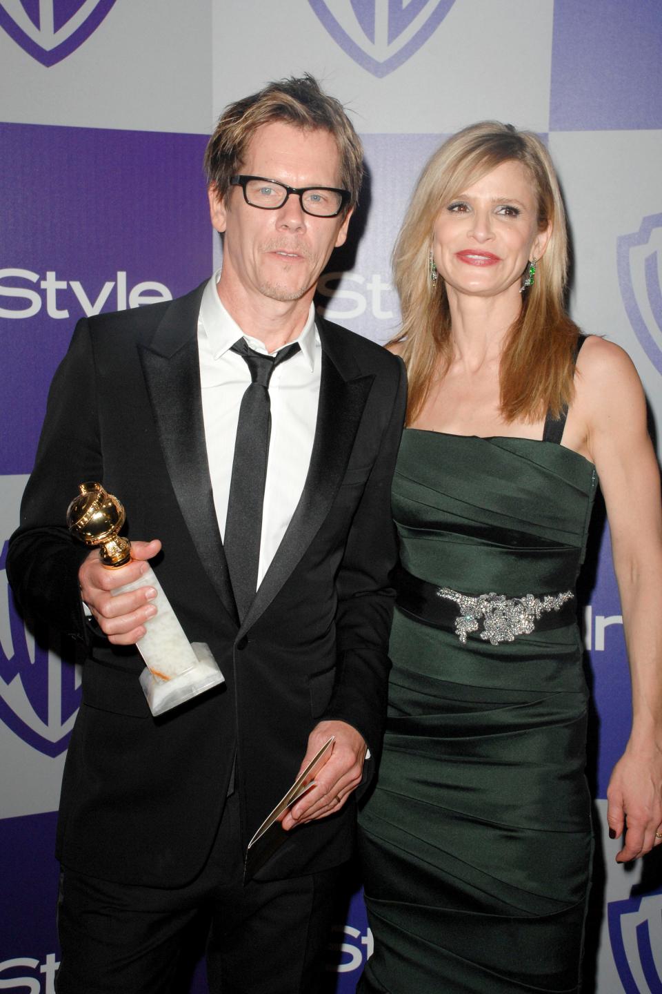 Kevin Bacon holding a Golden Globe standing next to Kyra Sedgwick