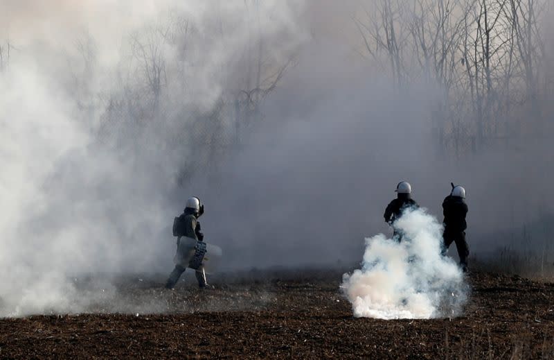 Greek riot police officers walk amid clouds of tear gas near Turkey's Pazarkule border crossing, in Kastanies