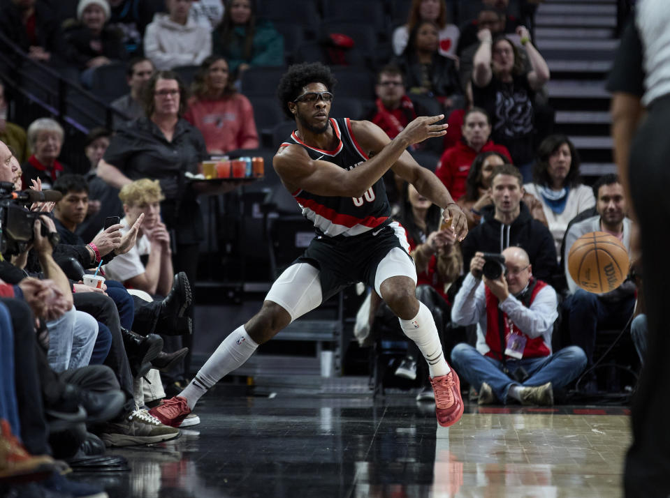 Portland Trail Blazers guard Scoot Henderson, center, saves the ball from going out of bounds during the first half of an NBA basketball game against the Phoenix Suns in Portland, Ore., Sunday, Jan. 14, 2024. (AP Photo/Craig Mitchelldyer)