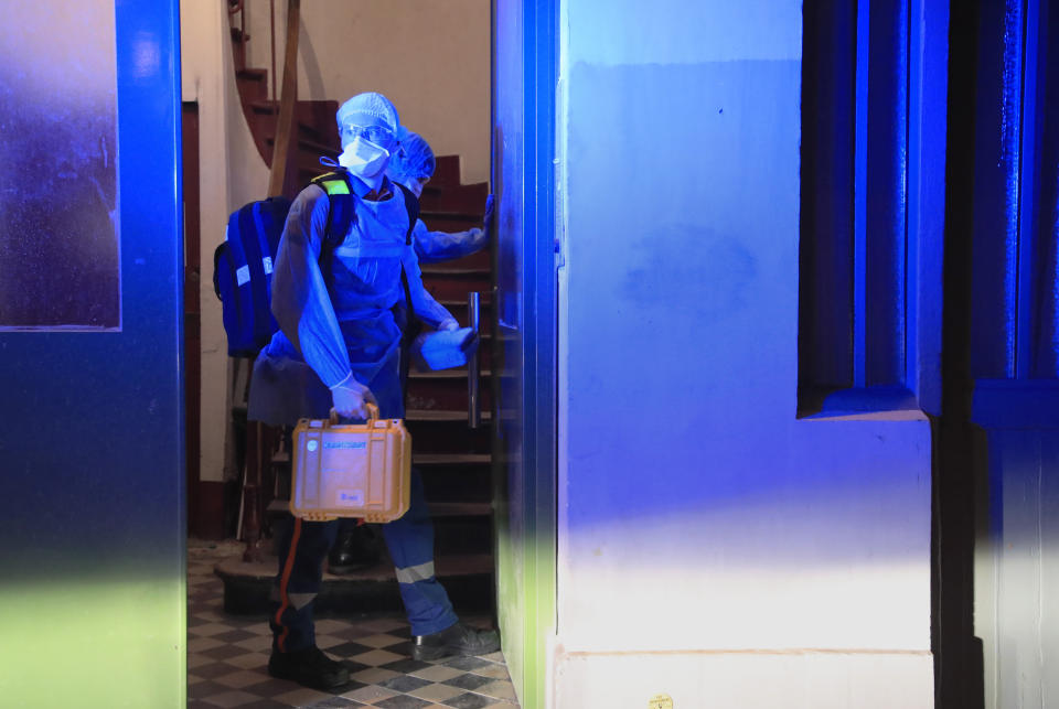 In this photo taken on Thursday, March 26, 2020 members of the Civil Protection service, Vincent Jactel, left, and Aurore Lejeune, right, enter a flat to evacuate a man suspected of having the coronavirus infection in Paris. (AP Photo/Michel Euler)