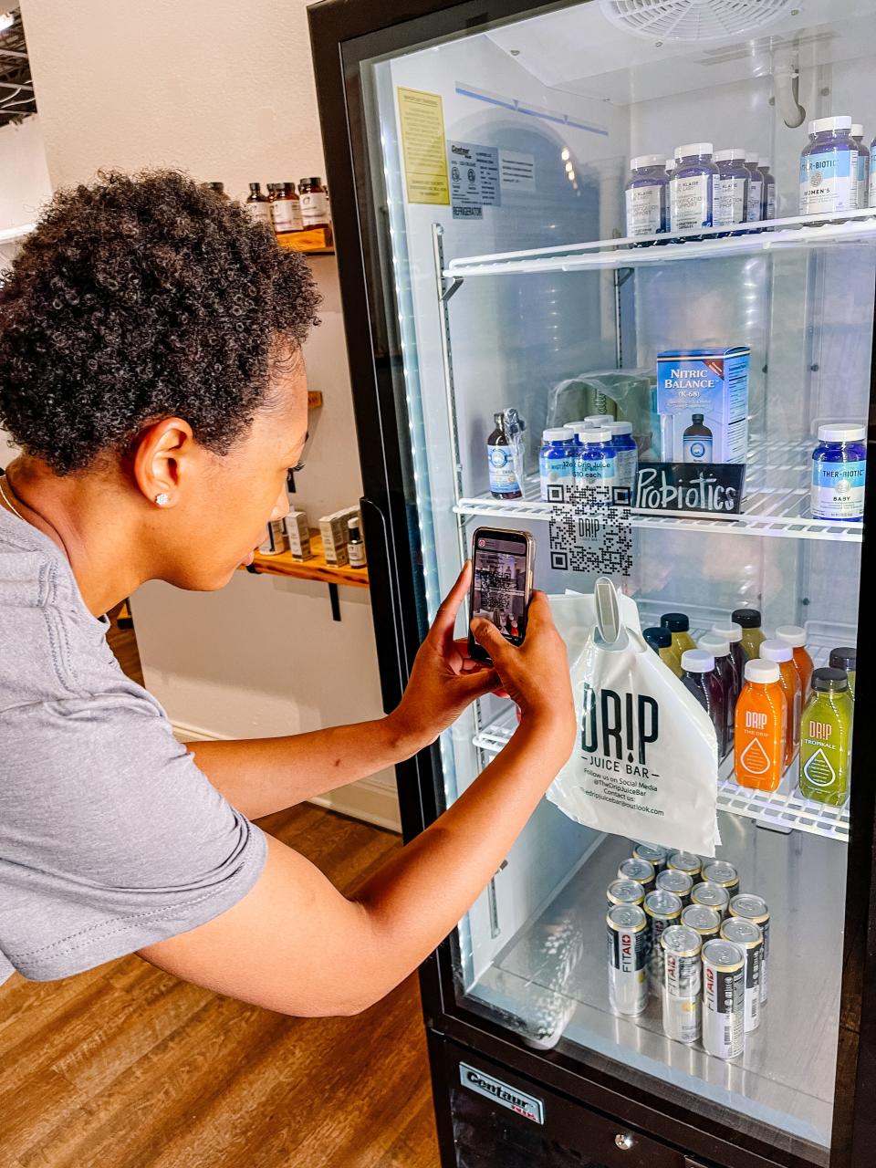 Drip Juice Bar owner Alexis Gillespie demonstrates how to purchase her juices after hours using a QR code at the Health Factory in South Knoxville, April 25, 2023.