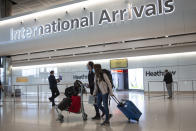 FILE - In this file photo dated Monday, June 8, 2020, passengers wearing face masks arrive at London's Heathrow Airport. The two-week quarantine period that travelers arriving in England from a destination not on the British government’s coronavirus safe list could be cut to just five days if they test negative for COVID-19. The change to the quarantine rules, which was announced Tuesday Nov. 24, 2020, and comes into force on Dec. 15, has been long-awaited by the travel industry, one of the worst-hit sectors during the pandemic. (AP Photo/Matt Dunham, File)