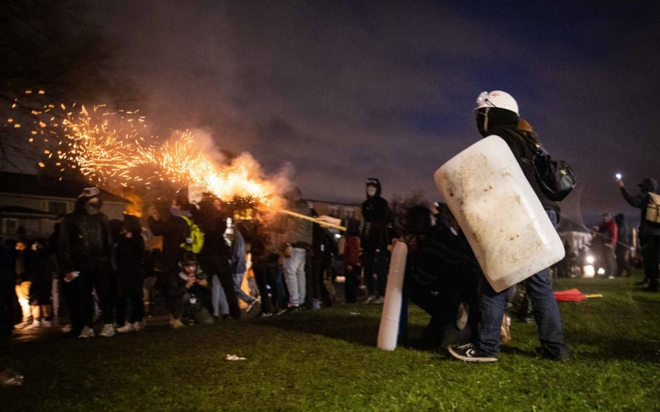 Demonstrators launch fireworks towards members of the National Guard during a protest in Brooklyn Center