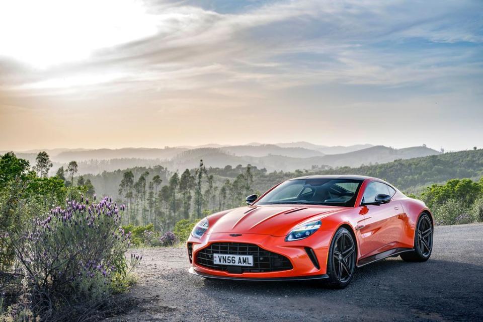 a red sports car parked on a road with trees and hills in the background